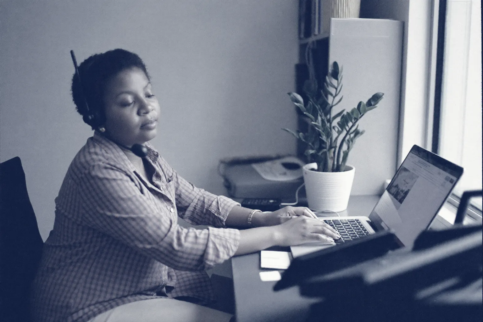 A staff member wearing a telephone headset at the front desk of a small business, mid-conversation with a customer — the moment a handover lands with full context.